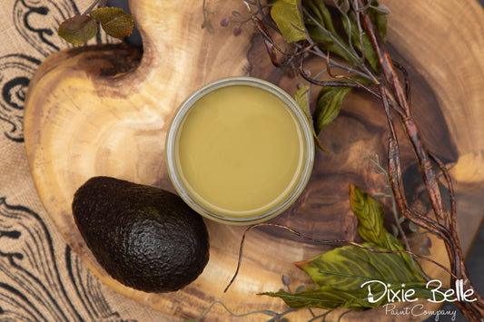 Dixie Belle paint color Holy Guacamole with avocado on a wooden surface, featuring the Dixie Belle Paint Company logo.