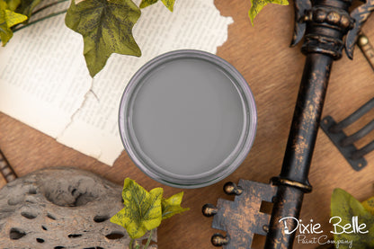 Gray paint can lid on a rustic background with decorative elements and 'Dixie Belle Paint Company' branding.