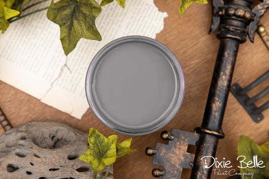 Gray paint can lid on a rustic background with decorative elements and 'Dixie Belle Paint Company' branding.