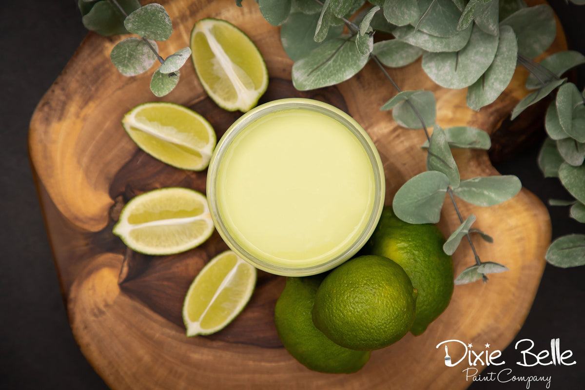 Wooden board with sliced limes and a container of green paint, featuring the Dixie Belle Paint Company logo.