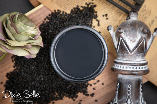 Dixie Belle paint Midnight Sky with rose, and seeds on a wooden surface. 
