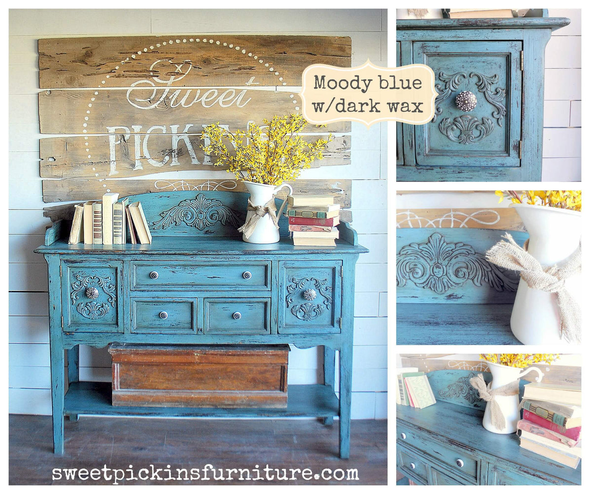A rustic distressed teal-blue wooden sideboard console table shown in a styled room setting, with decorative books, a white pitcher of yellow flowers, and a wooden crate underneath. The collage includes close-up inset views of the cabinet front and a text label reading 'Moody blue w/dark wax.