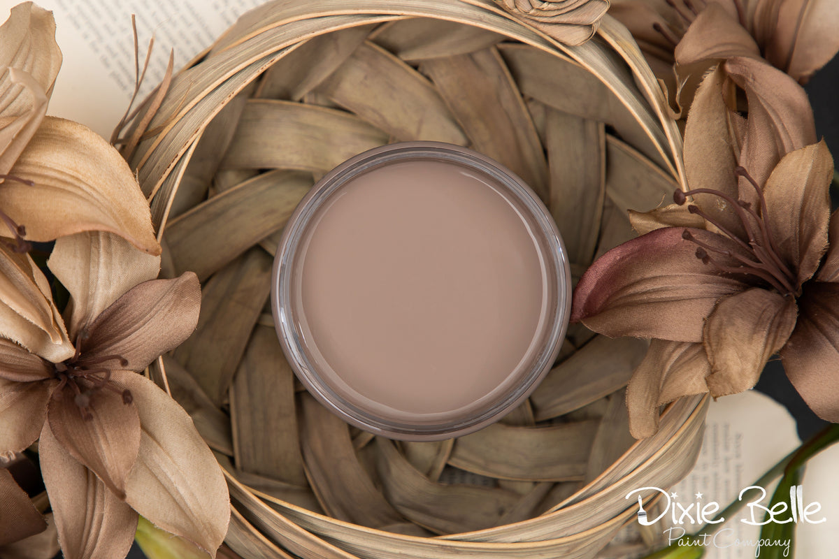 Dixie Belle Paint color Mud Puddle on a woven mat surrounded by flowers, featuring 'Dixie Belle' branding.