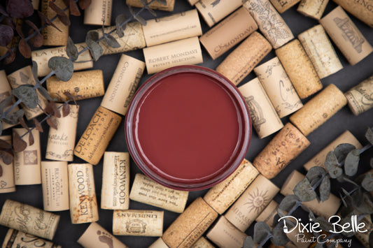 Dixie Belle Paint Muscadine Wine surrounded by wine corks on a dark surface