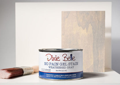 Dixie Belle No Pain Gel Stain can with a brush and stained wood panel on a gray background