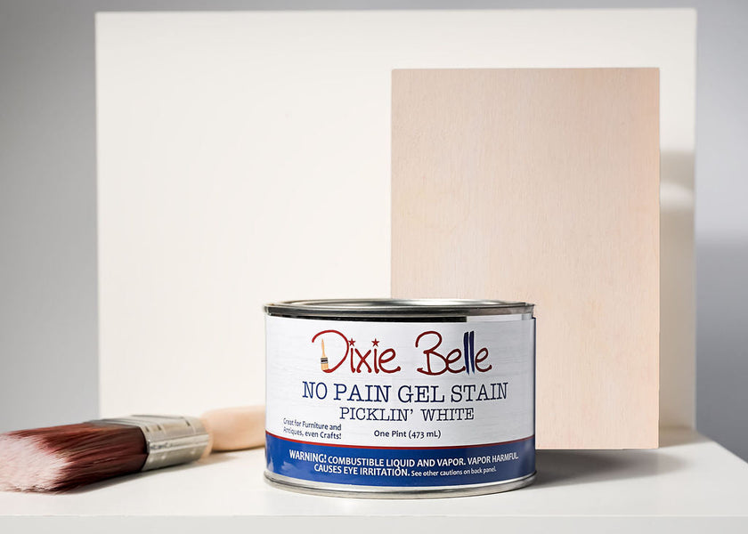 Dixie Belle No Pain Gel Stain can with a brush and wood panel in the background