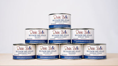 Eight Dixie Belle No Pain Gel Stain cans arranged in a pyramid stack on a light beige surface against a white background.
