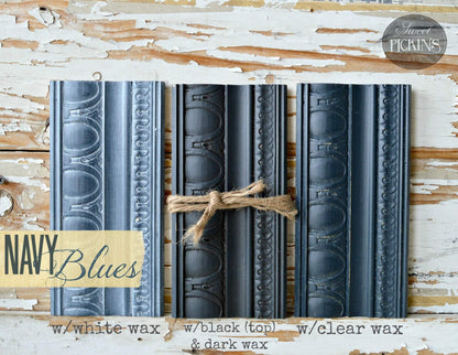 Three decorative navy blue frame panels with embossed scrollwork, arranged side by side on a distressed white wood background. A jute rope ties the center panel.