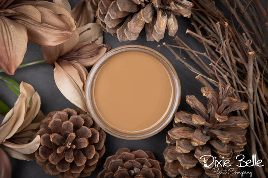 Jar of Dixie Belle Paint Pine Cone surrounded by pinecones and twigs on a dark surface with 'Dixie Belle Paint Company' branding.