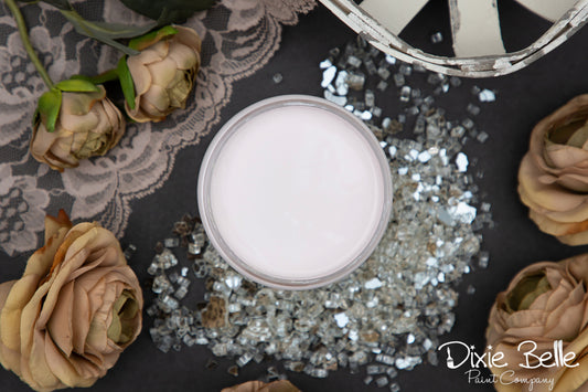 Dixie Belle Paint color Pink Champagne on a decorative surface with flowers and glitter, featuring 'Dixie Belle'.