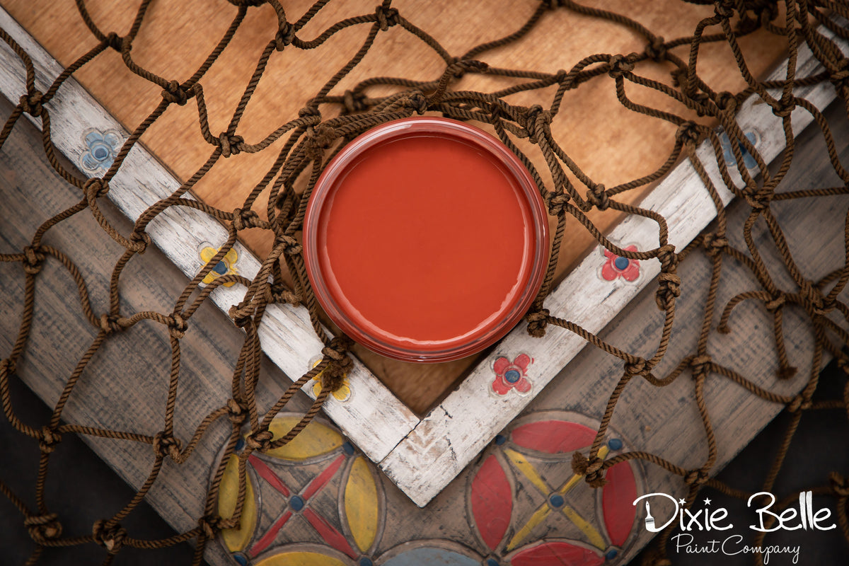 Dixie Belle Paint color Rusty Nail can on a textured surface with decorative elements