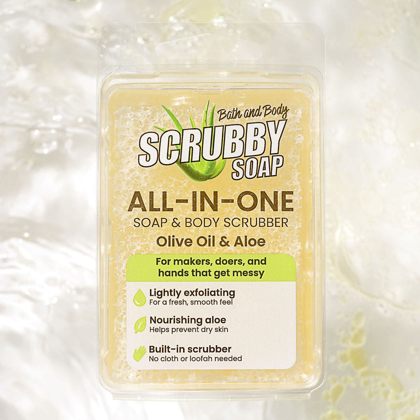 A clear plastic tub of Bath and Body Scrubby Soap All-In-One Soap & Body Scrubber, featuring an olive oil and aloe scent, set against a textured white background with soap bubbles.