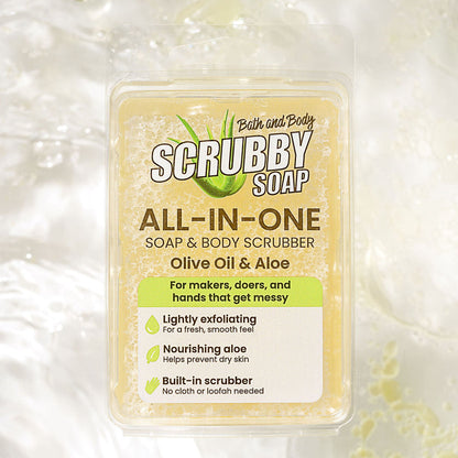 A clear plastic tub of Bath and Body Scrubby Soap All-In-One Soap & Body Scrubber, featuring an olive oil and aloe scent, set against a textured white background with soap bubbles.