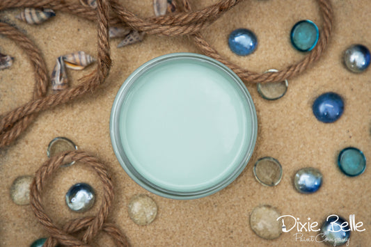 Dixie Belle Paint color Sea Glass on a textured surface with decorative elements like rope and stones.