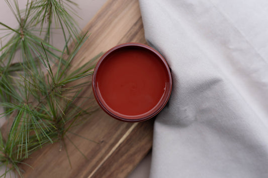  'Sequoia' paint on a wooden surface with a plant and white fabric in the background