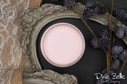 Pink paint can inside an ornate frame with decorative elements on a dark background