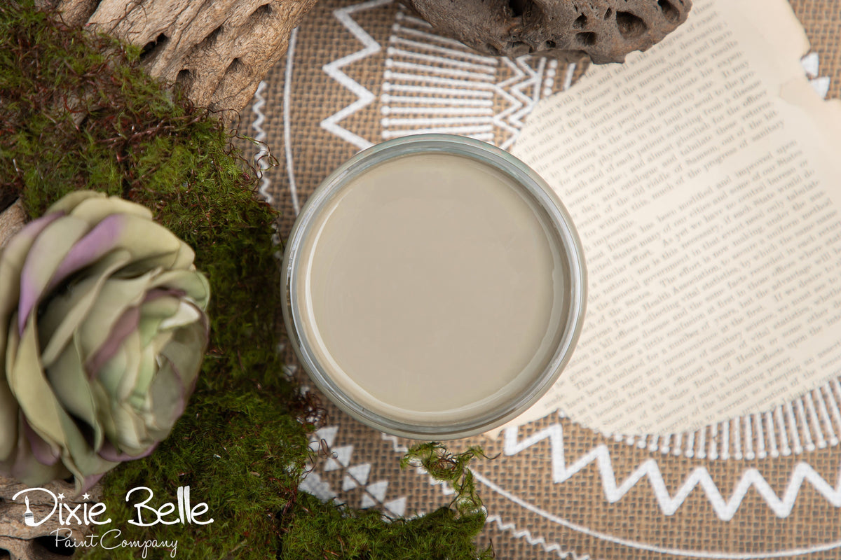 Dixie Belle Paint color Spanish Moss Jar of paint with a decorative mat and plant in the background, featuring the Dixie Belle Paint Company logo.
