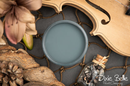 Dixie Belle paint color swatch labeled 'Stormy Seas' with floral and wooden elements.