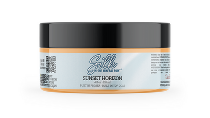 A jar of Silk All-In-One Mineral Paint in Sunset Horizon, featuring a black lid and a label with a light blue center and orange bands on the sides.