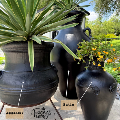 Three matte black decorative ceramic pots in different shapes, shown outdoors with plants. The pots are labeled 'Eggshell', 'Satin', and the image includes the brand name 'Tracey's Fancy' at the bottom.