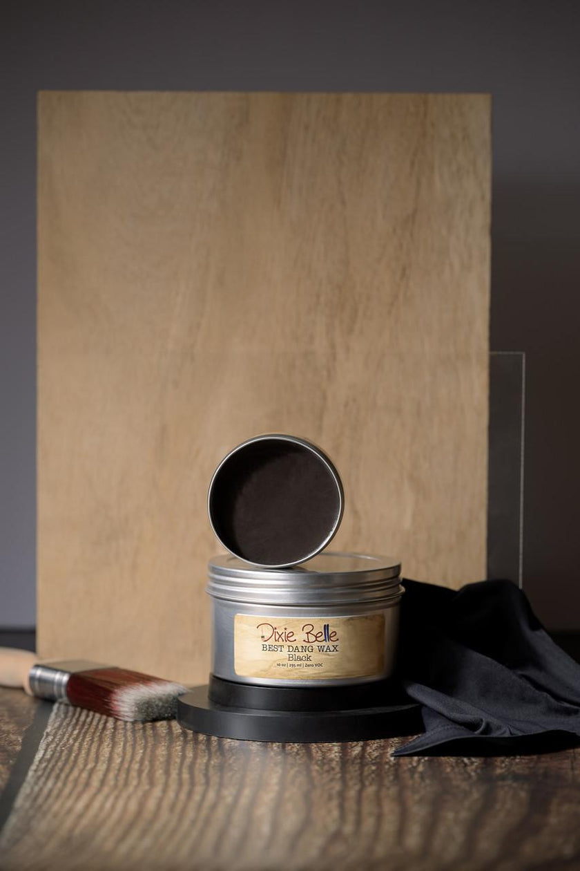 Wax tin with a wooden board and black cloth in the background