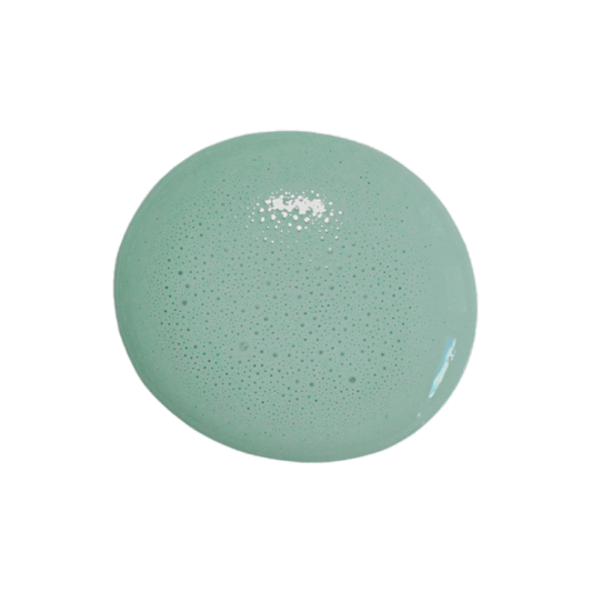 A single round drop of Birdie milk paint with tiny air bubbles, shown on a solid white background.