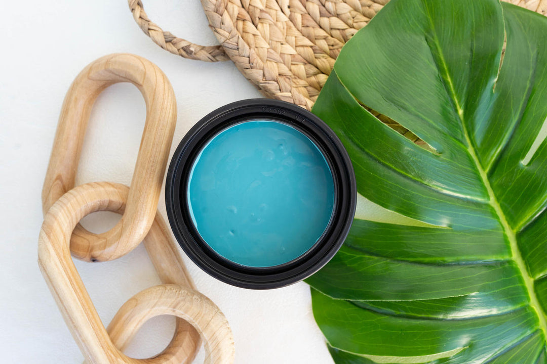 Cerulean Blue Terra Clay Paint on a white surface with a green leaf and wooden object.