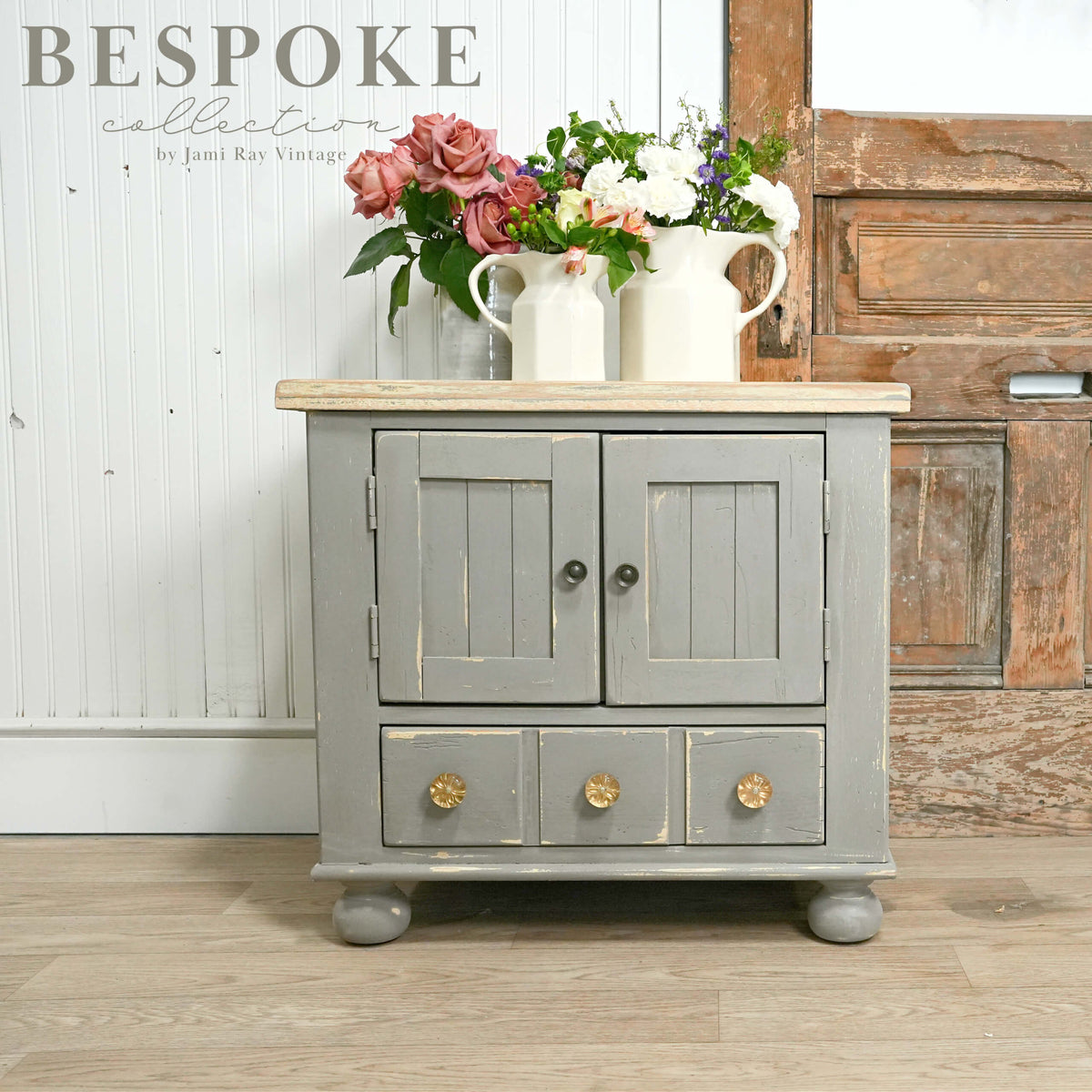 Gray cabinet with wooden top and flowers, labeled 'Bespoke collection by June Rae Vintage'.