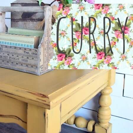 Yellow wooden table with a decorative sign reading 'Curry' against a floral background.
