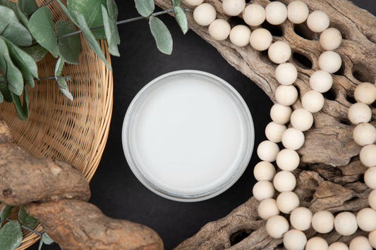 White container on a dark surface with natural elements like wood, stones, and plants.