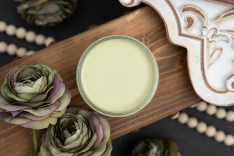 Small jar of cream on a wooden tray with decorative elements