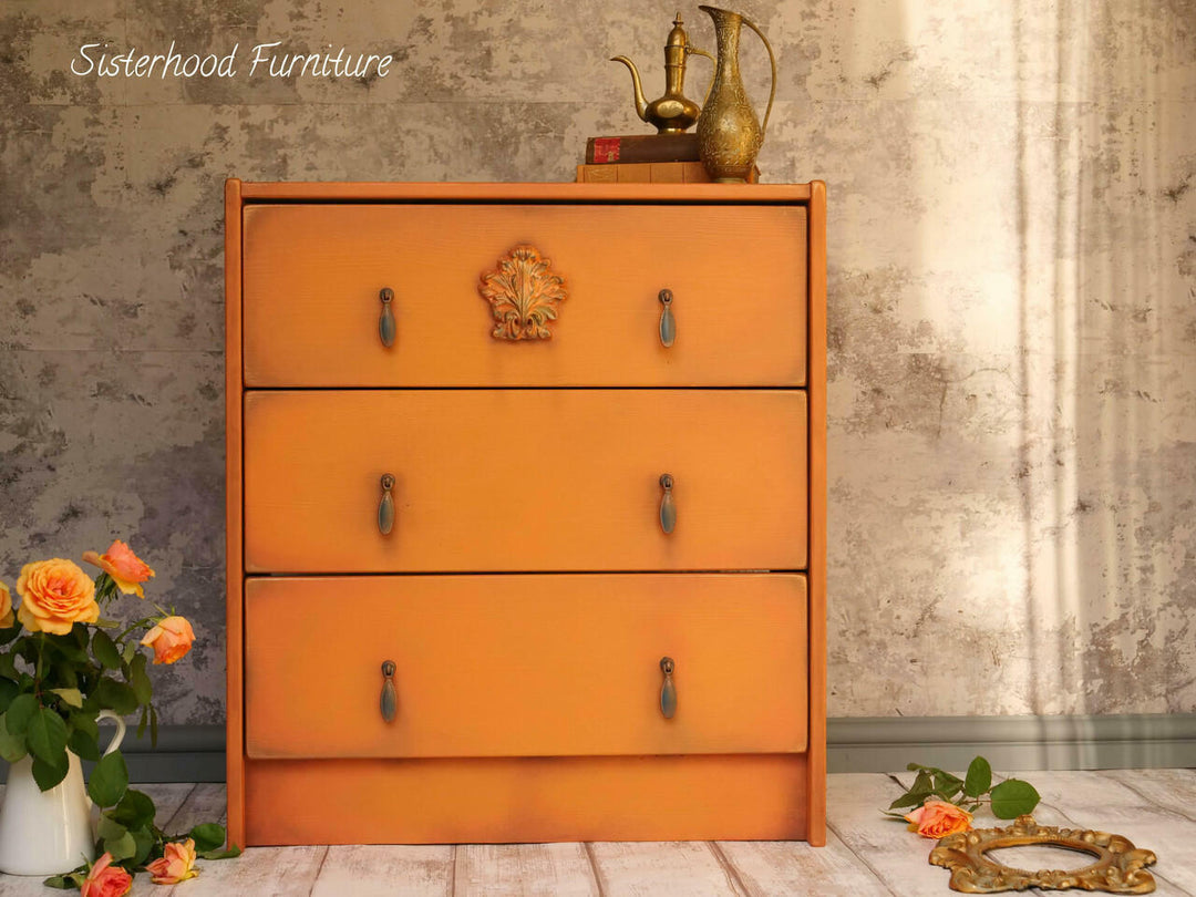 Orange dresser with decorative elements against a textured wall.