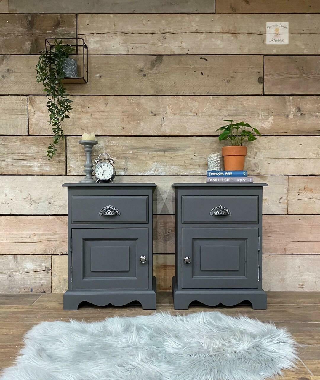 Two gray nightstands with decorative items against a wooden wall.