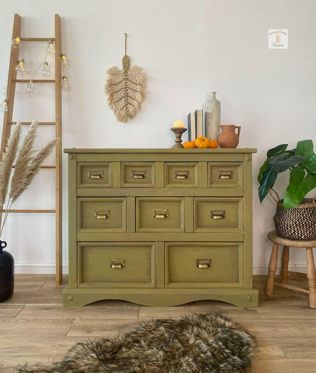 Green dresser in a room with decorative items and plants