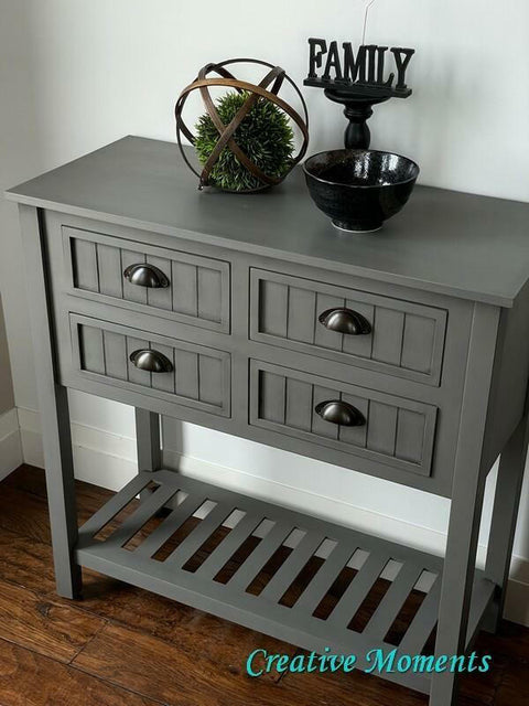 Gray side table with decorative items on a wooden floor
