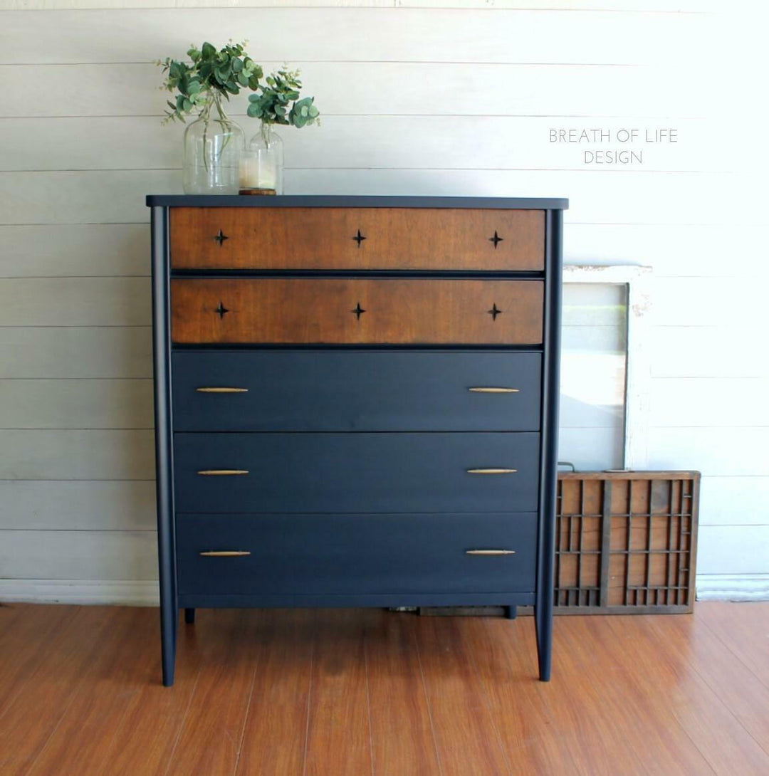 Two-toned dresser with wooden top and navy base on a wooden floor.