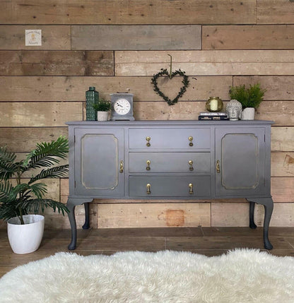 Gray sideboard with decorative items against a wooden wall.