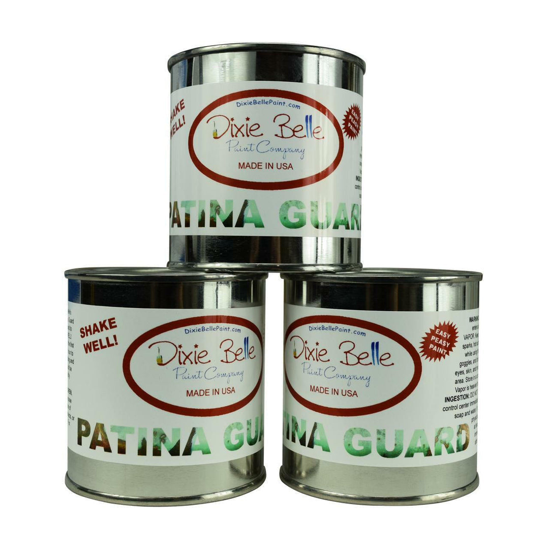 Three metal cans of Dixie Belle Patina Guard paint company product stacked in a pyramid on a white background.