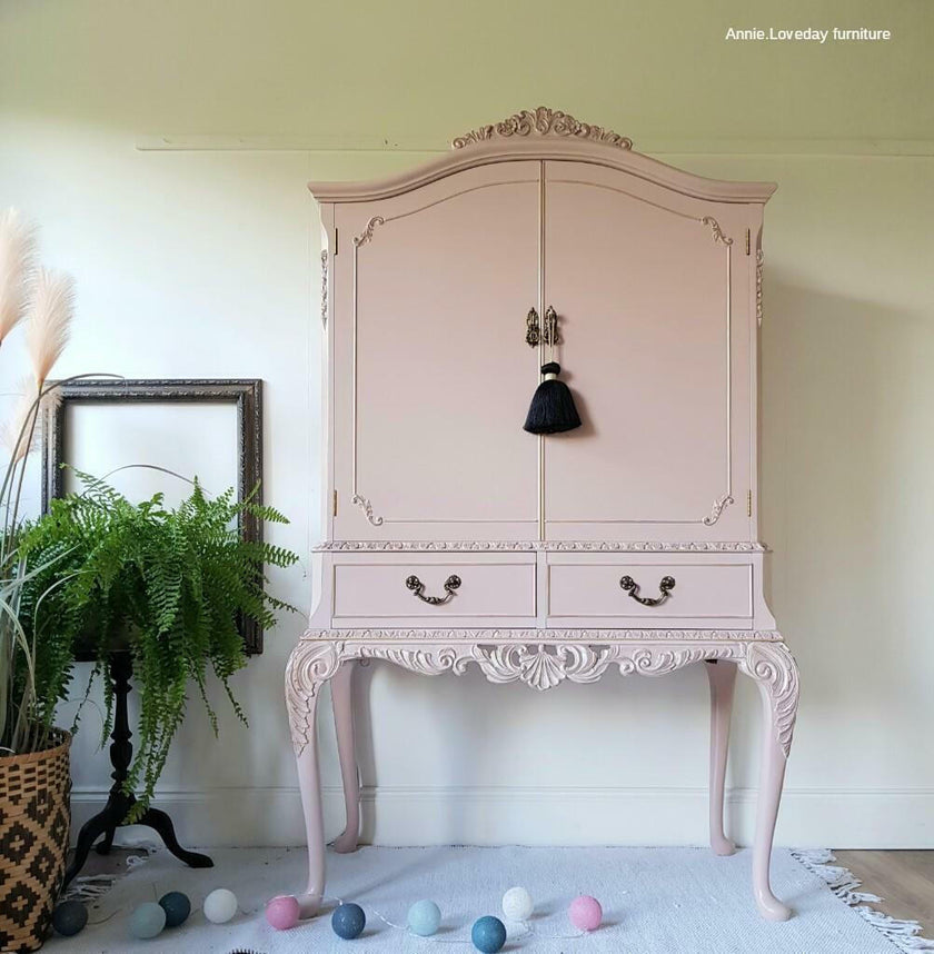 Pink ornate cabinet with decorative elements in a room setting