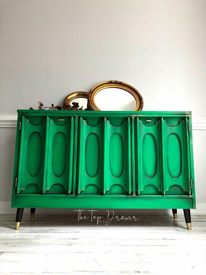 Green dresser with gold legs against a white wall, featuring 'The Top Drawer' brand.
