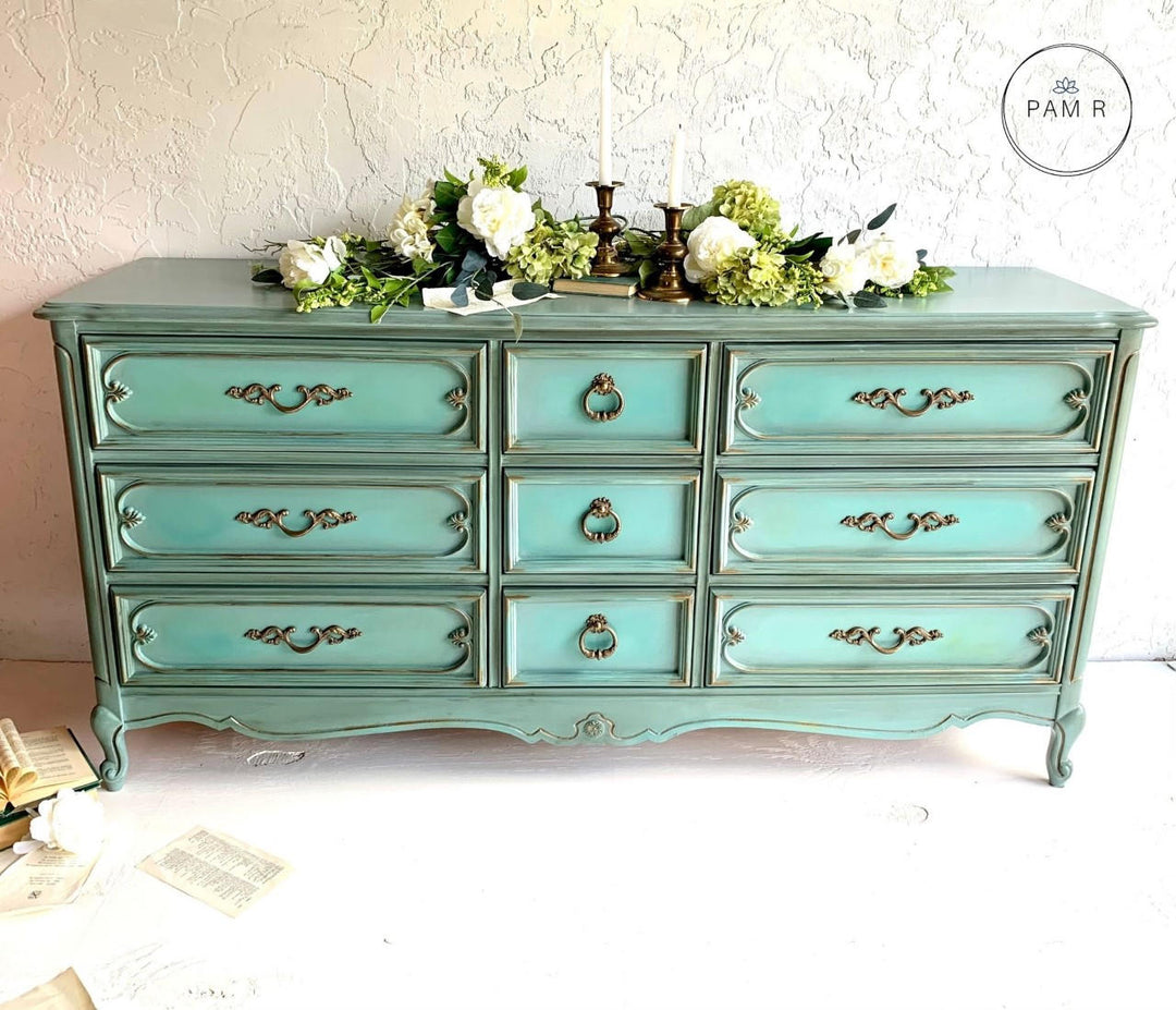 Turquoise dresser with decorative items on a white background