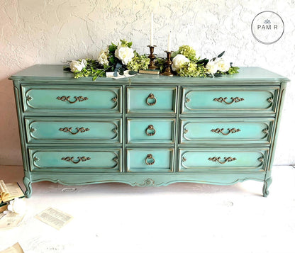 Turquoise dresser with decorative items on a white background
