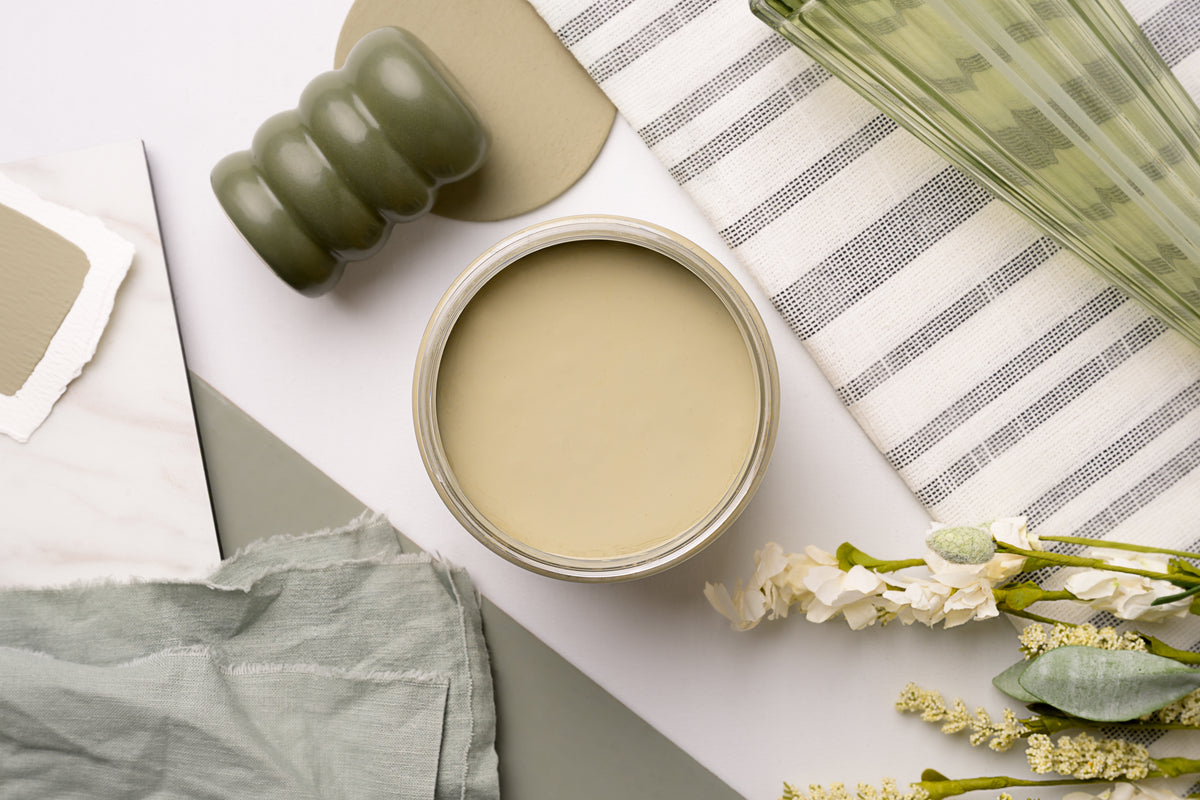 Dixie Belle Paint color Olive Wood with a green roller, towel, and flowers on a light surface