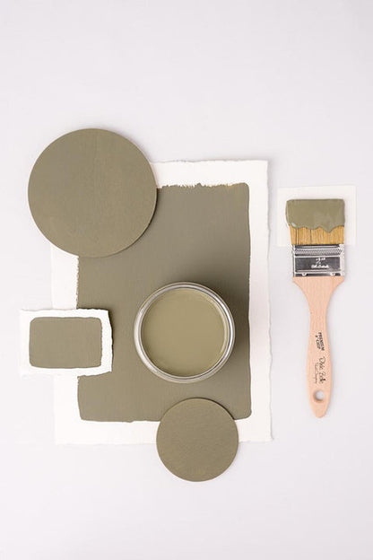 Sage green paint sample with a brush on a white background