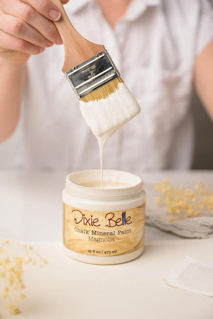 Person using a brush to apply Dixie Belle Chalk Mineral Paint to a container.