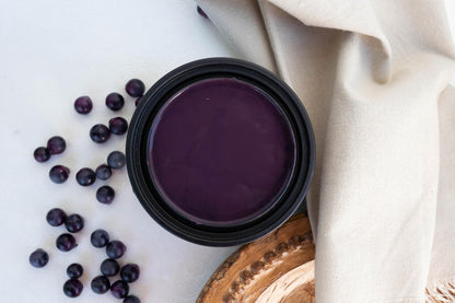 Elderberry Terra Clay Paint, styled on a white surface with scattered blueberries and a beige fabric napkin.