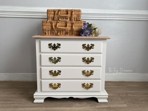 White dresser with gold handles on a wooden floor against a gray wall.