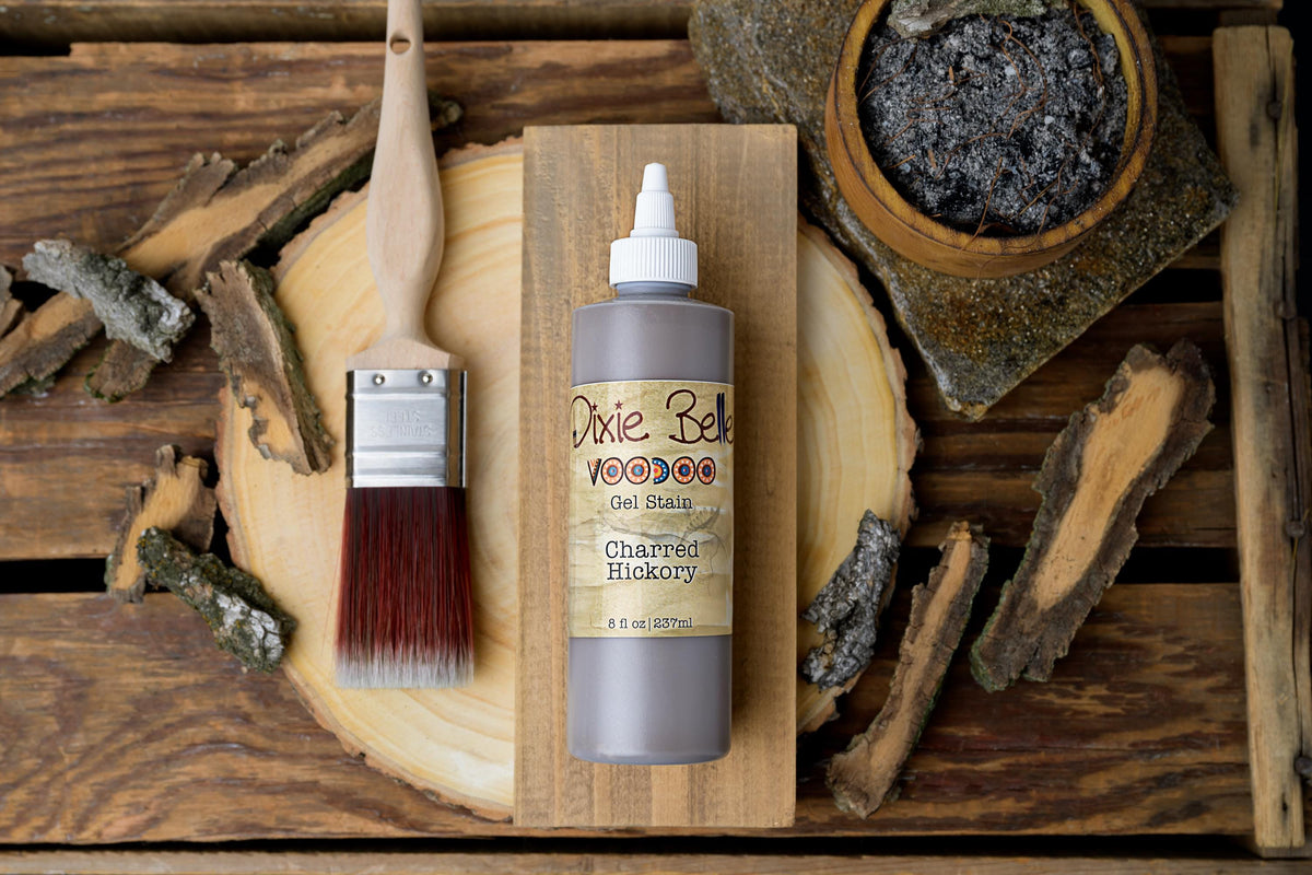 Wooden bottle of Dixie Belle Charred Hickory gel stain with brush on a wooden surface.