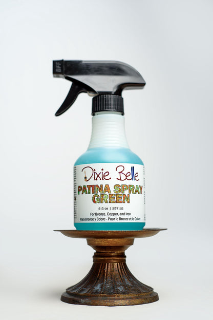 Dixie Belle Patina Spray Green bottle on a wooden stand with a white background