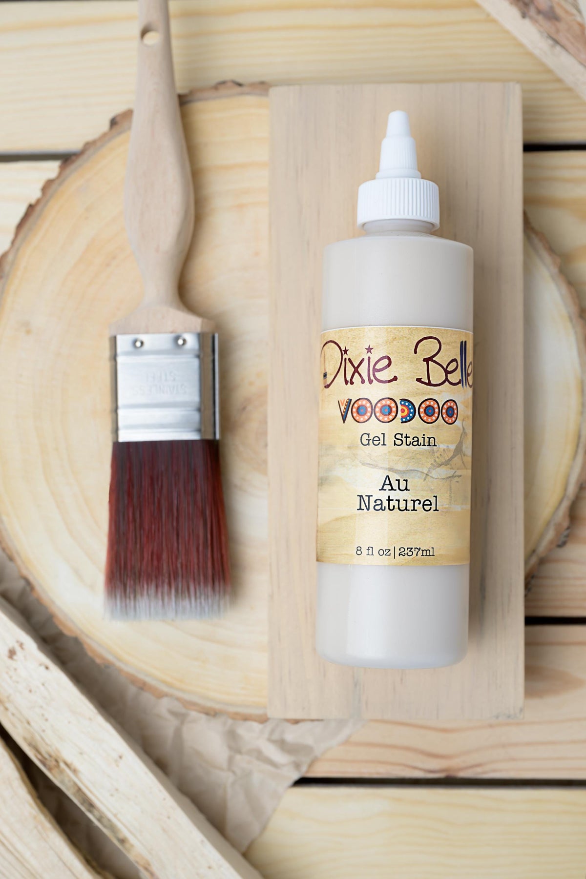 Bottle of Dixie Belle Au Naturel Voodoo Gel Stain and brush on a wooden surface